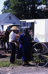 Amish man and woman with white top buggy by Dennis L. Hughes