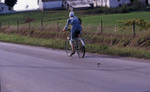 Amish woman bicycling by Dennis L. Hughes