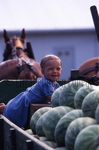 Smiling Amish girl with watermelons by Dennis L. Hughes