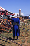 Amish woman inspecting buggies at mud sale by Dennis L. Hughes