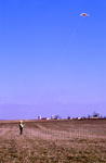 Amish boy flying kite in field by Dennis L. Hughes
