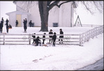 Group of children sled under fence by Dennis L. Hughes