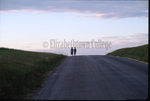 Amish girls walk in distance by Dennis L. Hughes